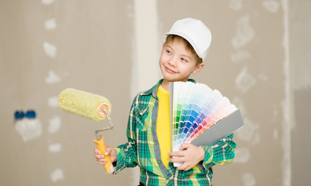 Boy with color samples and paint roller chooses the color of the walls of his room.